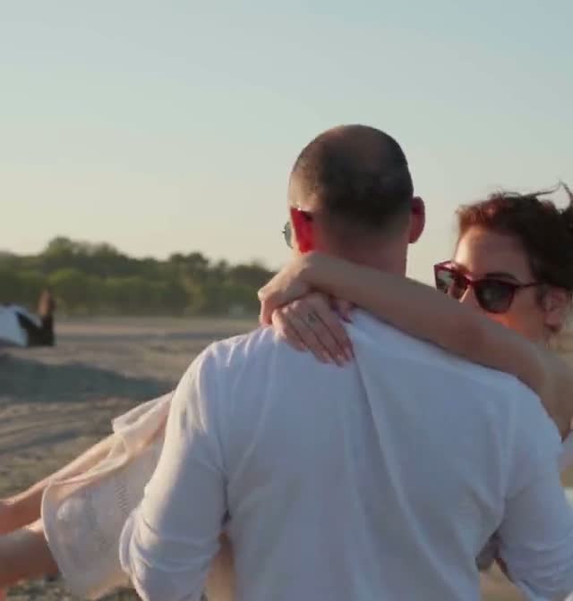 He spins her around on the beach at sunset