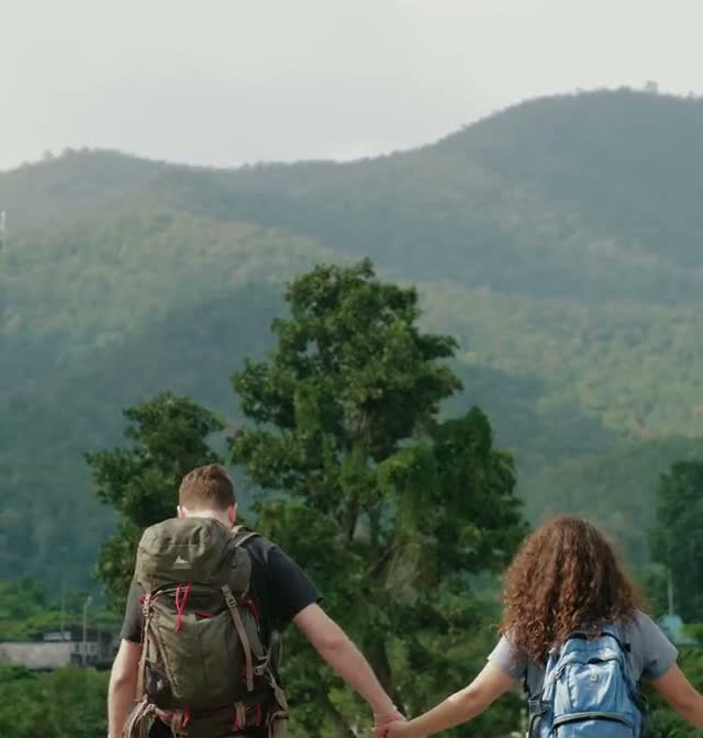 A couple walking hand in hand along a railway in the hills